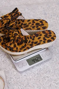 Detailed shot of leopard print bow wedge slipper weighing 442.4g on a digital scale