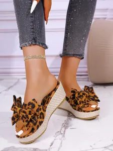 Detail shot of leopard print wedge slippers with a large bow on model's feet.