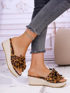 Detail view of leopard print wedge slide sandals with decorative bow and jute platform