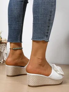 Side view detail of white platform wedge sandals featuring a stylish bow and woven sole.