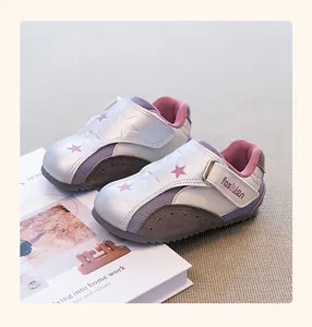 Close-up view of stylish girls' silver sneakers with purple star accents and velcro straps