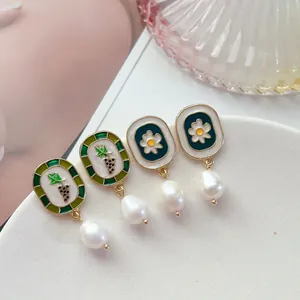 Gros plan détaillé de boucles d'oreilles vintage en émail avec motif raisin et perles baroques