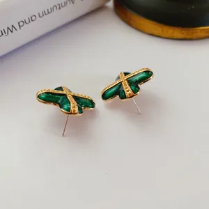 Nahaufnahme von grünen Emaille-Ohrsteckern im Barockstil mit goldenem Kreuz