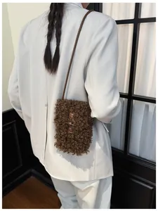 Detail of brown curly faux fur crossbody phone bag with retro horn button closure.
