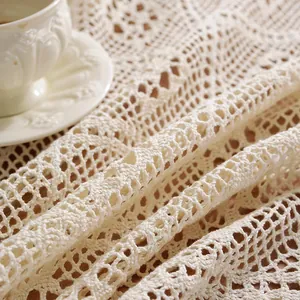 Primer plano de un mantel de encaje de ganchillo beige con motivos florales calados
