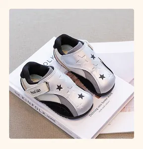 Top view of silver girl's sneakers with star patterns on a minimalist lifestyle book