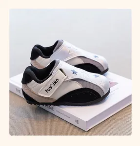 Detail view of silver and black girls' sporty German Army Trainer shoes on book prop
