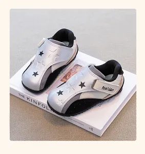 Close-up of silver and black girls' sneakers with star patterns placed on a white book