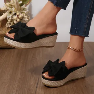 Elegant black wedge sandals for women featuring a large bow and woven platform sole