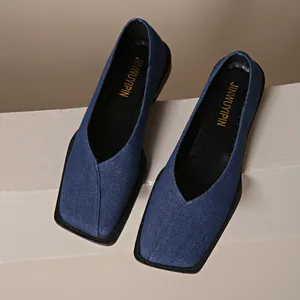 Gros plan de mocassins en denim bleu avec un bout carré et une semelle noire confortable