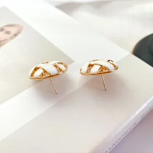 Detailed view of vintage gold woven earrings with white enamel and silver posts