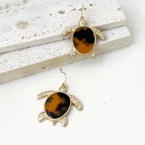 Detalle de pendientes de tortuga vintage en tono dorado con diseño de carey sintético