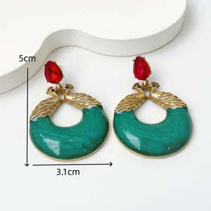 Vista detallada de pendientes vintage de pavo real en resina verde con piedras rojas
