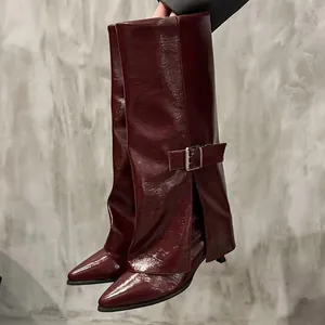 Detailed view of burgundy trouser leg boots with pointed toe and silver belt buckle.