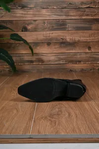 Detailed close-up showing the anti-slip outsole and chunky heel of black pointed toe boots