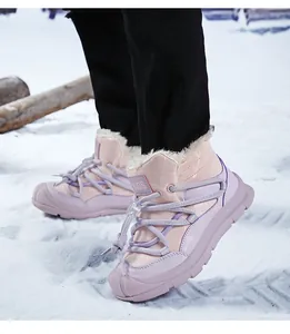 Close-up of pink kids' snow boots with thick faux fur lining in a snowy landscape