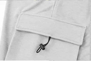 Detail view of cargo pocket flap and adjustable drawstring on gray outdoor pants