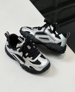 Κοντινό πλάνο παιδικών ασημί mesh sneakers με μαύρες λεπτομέρειες και χοντρή σόλα.