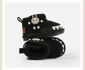 Detailed view of black children's snow boots with monster charm and teeth design