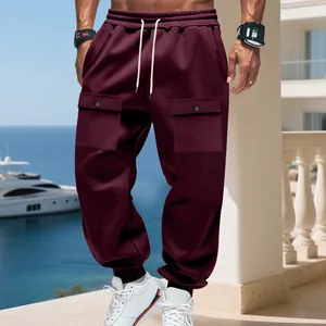 Dettaglio dei pantaloni cargo pesanti da uomo bordeaux con grandi tasche a patta laterali.