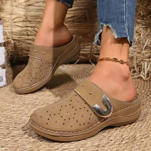 Detailed view of vintage tan platform clogs with floral laser-cut details and buckle.