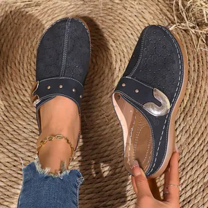 Macro detail of retro platform closed-toe clogs featuring embossed floral patterns and metal buckle