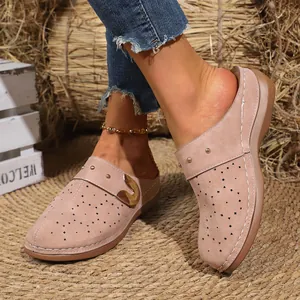 Detail of French retro pink mules featuring laser-cut floral patterns and gold buckle