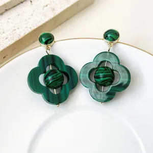 Détail rapproché des boucles d'oreilles trèfle vintage avec motif malachite
