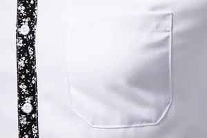 Close-up of white men's shirt showing chest pocket and black floral placket detail