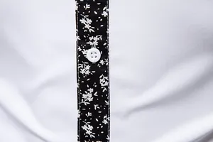 Close-up detail of white men's shirt with black floral patchwork placket and button