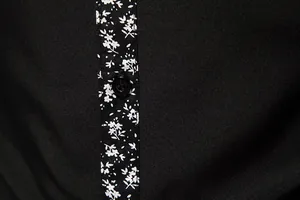 Detailed macro view of the white floral print on a black men's casual shirt placket