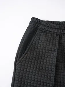 Macro detail of black waffle knit trousers showing elastic waistband and side pocket