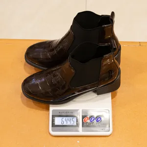 Medición del peso de los botines brillantes marrón oscuro con patrón de cocodrilo en báscula