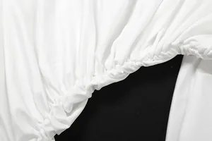 Close-up of elastic pleated waist detail on white high-neck elegant top and skirt set.