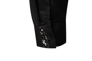 Macro view of men's black shirt cuff showing white paisley pattern and button detail.