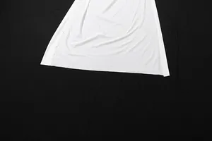 Macro detail view of white pleated high slit skirt hem fabric on black background