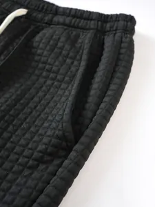 Close-up detail showing the textured waffle knit fabric and drawstring of black casual pants