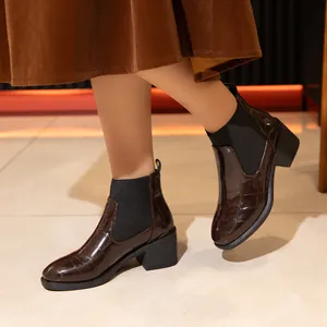 Primer plano de botines marrón oscuro con relieve de cocodrilo y tacón grueso moda