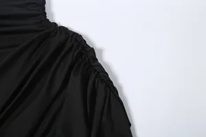 Close-up detail of the elegant pleated fabric texture on a solid black high-neck top