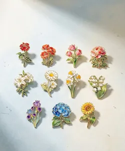 Detailansicht verschiedener bunter Blumen-Emaille-Anstecknadeln auf blauem Grund