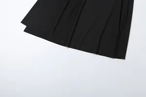 Close-up detail showing the smooth black fabric and hemline of a draped maxi skirt