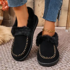 Close-up of black suede winter loafers with faux fur trim and gold chain detail