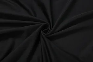Close-up detail of smooth black fabric with elegant spiral draping textile texture