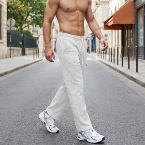 Macro view of light gray waffle-knit casual trousers on a male model outdoors
