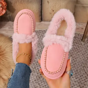 Close-up of pink suede winter loafers with plush faux fur trim and stitched details.