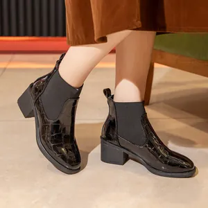 Primer plano de botines Chelsea en charol negro con grabado de cocodrilo y tacón ancho