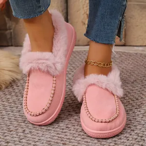 Close-up of pink suede winter slippers with fluffy fur trim and metallic chain detail.