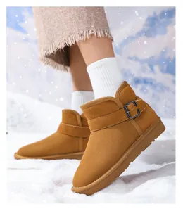 Close-up of warm kids tan leather snow boots featuring a decorative buckle strap in snow