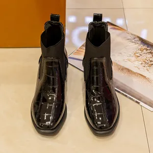 Vista de detalle de botines negros para mujer con grabado de cocodrillo y tacón ancho