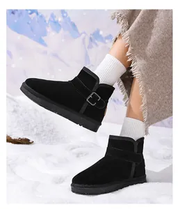 Side view of black kids leather snow boots with decorative buckle on snowy ground